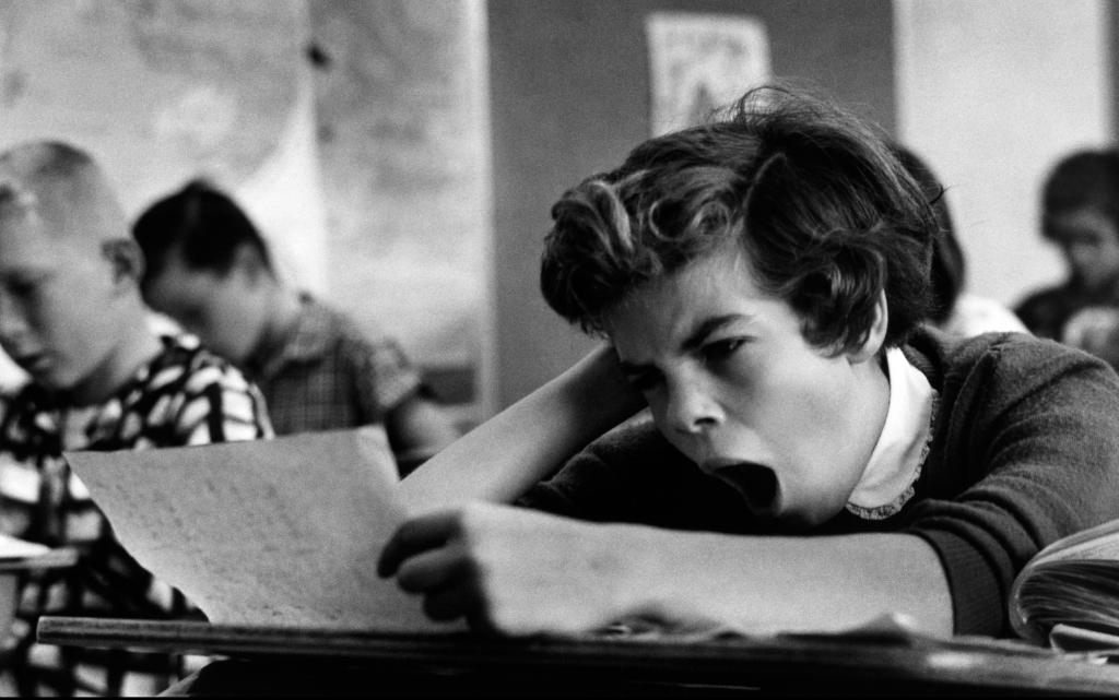 Ребенок зевает на уроке.