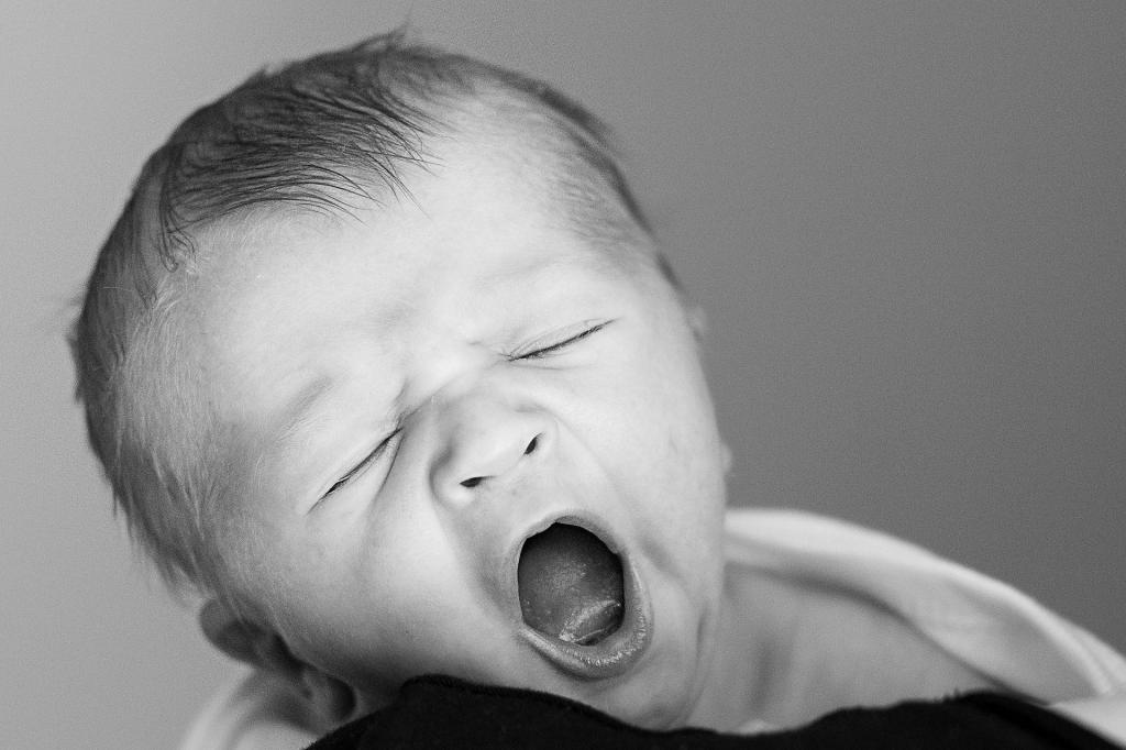 Новорожденный ребенок зевает.